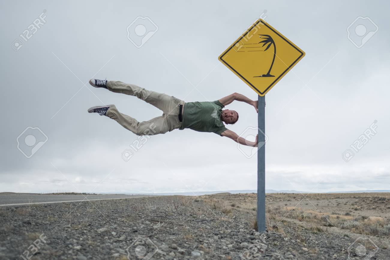 強風で有名な轟音40年代の緯度でパタゴニアの道路に設定された道路標識を楽しんでいる男 アルゼンチン の写真素材 画像素材 Image