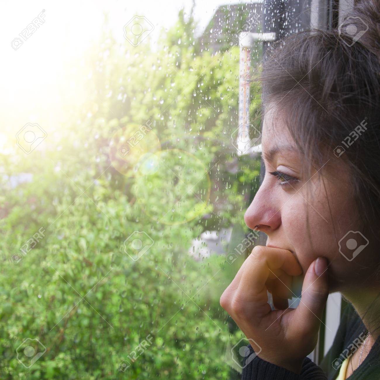 Sad girl looks out the window its raining. Woman with nice looking hear - 106640786 Sad girl looks out the window its raining. Woman with nice looking hear - 106640786