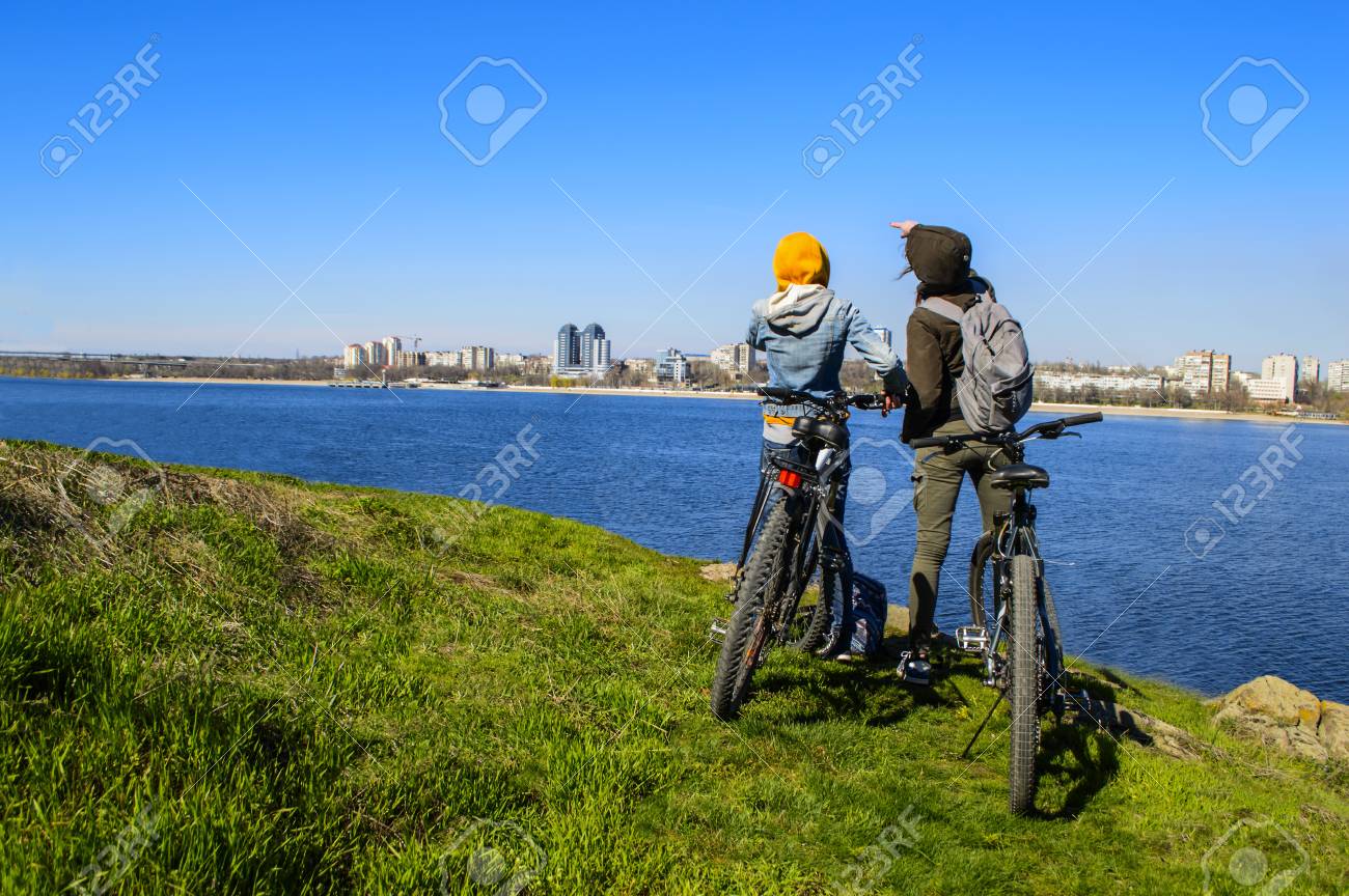 Happy Young Female Friends Riding Bicycles On The Seaside Road Women Enjoying Bikes Happy Young Female Friends Riding Bicycles On The Seaside Road Women Enjoying Bikes