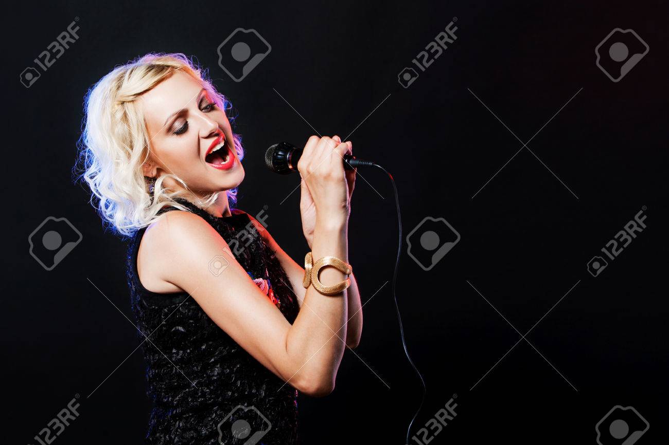 Schöne Frau mit Mikrofon singen Karaoke Singer Song auf schwarzem Hintergrund Schöne Frau mit Mikrofon singen Karaoke Singer Song auf schwarzem Hintergrund