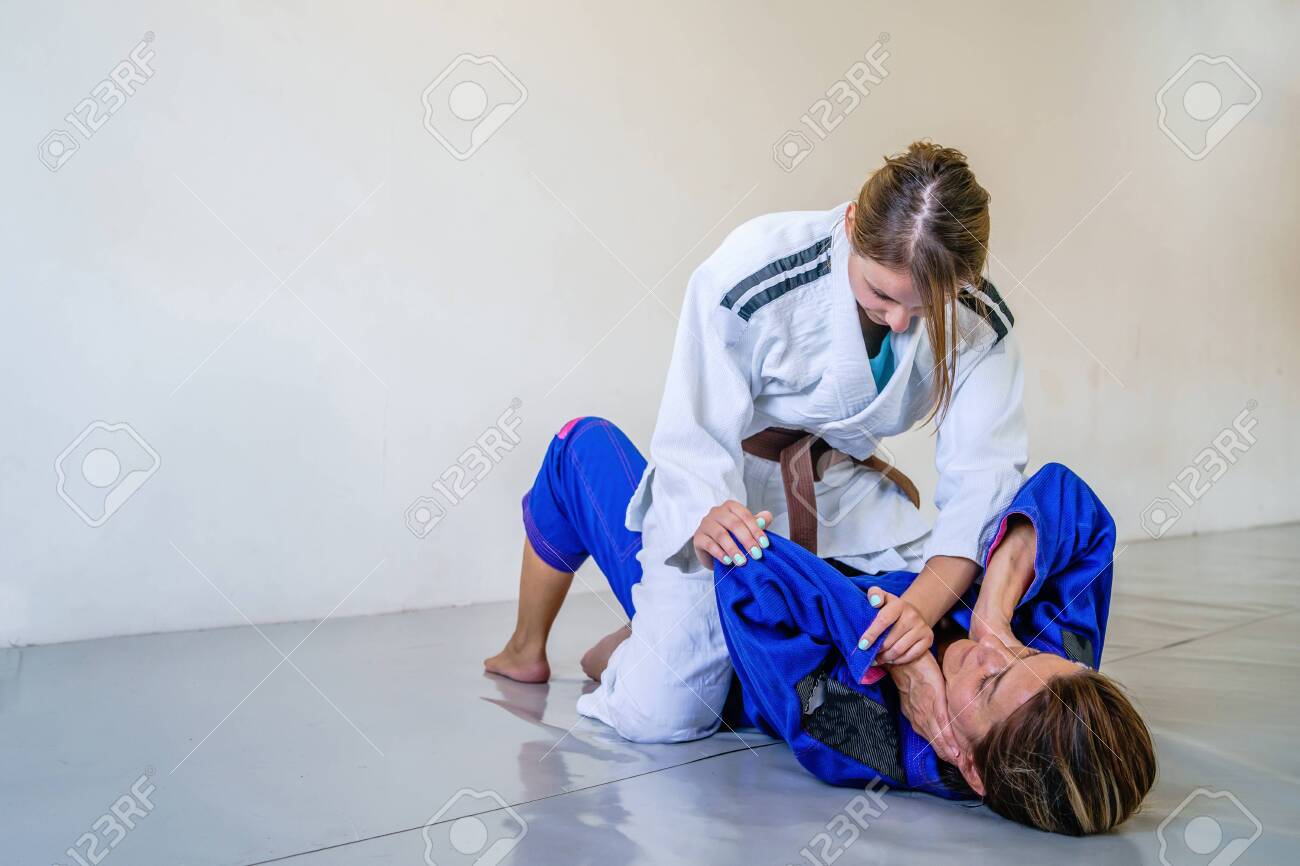 Two brazilian jiu jitsu BJJ women female athletes fighting in training spar...