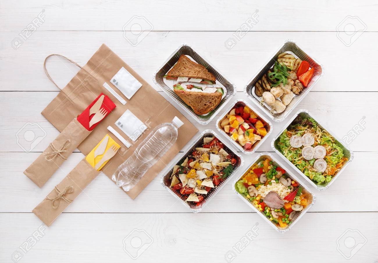 Healthy food delivery. Take away for diet. Fitness nutrition, vegetables, meat and fruits in foil boxes, cutlery, water and brown paper package. Top view, flat lay at white wood with copy space - 59486675 Healthy food delivery. Take away for diet. Fitness nutrition, vegetables, meat and fruits in foil boxes, cutlery, water and brown paper package. Top view, flat lay at white wood with copy space - 59486675
