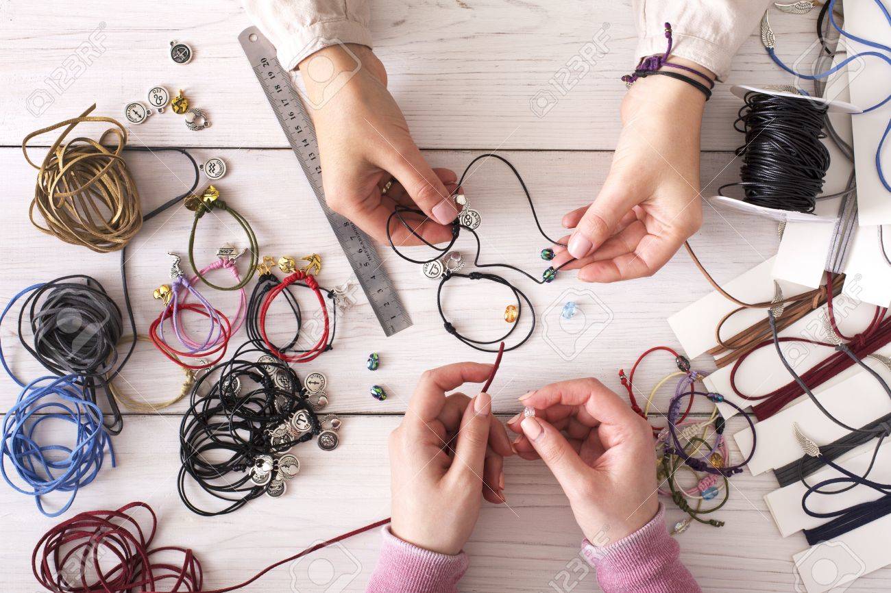 Fabrication de bijoux faits à la main, passe-temps féminin. Deux femmes créent des bijoux en atelier à domicile, vue de dessus sur le lieu de travail. Fabrication de bijoux faits à la main, passe-temps féminin. Deux femmes créent des bijoux en atelier à domicile, vue de dessus sur le lieu de travail.