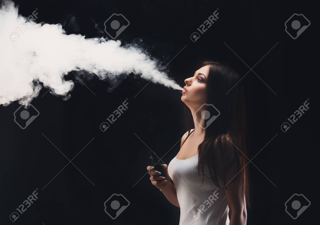 ブラックスタジオの背景に蒸気 Mod を持つ女の子 タバコをやめるために 若い女性が電子タバコを吸っている 蒸気および代わりとなるニコチン自由な喫煙の概念 コピースペース の写真素材 画像素材 Image
