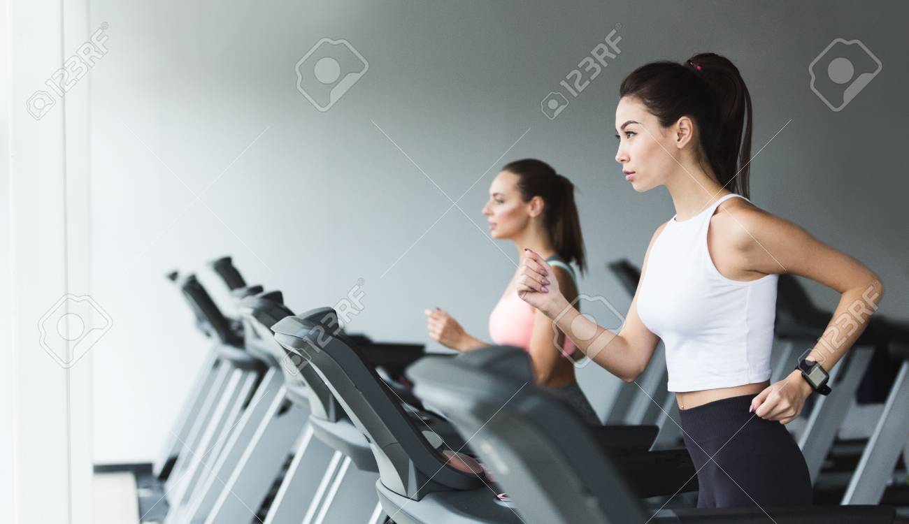 Fit women doing cardio workout, running on treadmill in gym, copy space - 115322067 Fit women doing cardio workout, running on treadmill in gym, copy space - 115322067