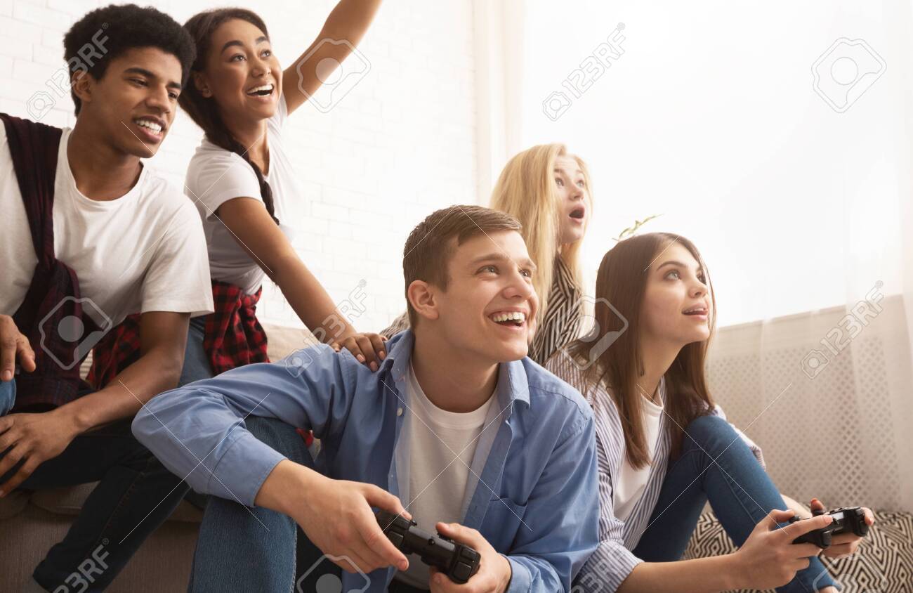 Playful friends playing video games online and having fun Stock