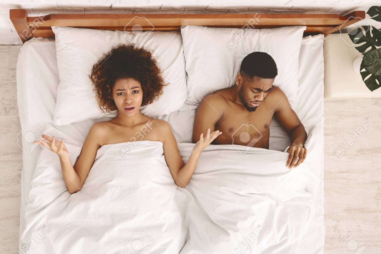黒人のセックス セックスの問題。ベッドに横たわっている失望した黒人の満足していない女性、毛布の下を見ている悲しい男、トップビューの写真素材・画像素材 Image  127874141