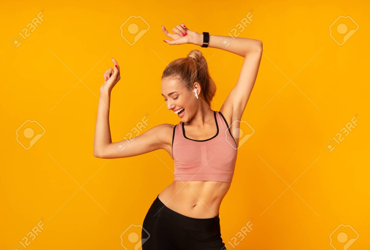 Sporty Woman In Wireless Earphones Dancing Listening To Music Over Yellow Studio Background. Free Space - 130405585 Sporty Woman In Wireless Earphones Dancing Listening To Music Over Yellow Studio Background. Free Space - 130405585