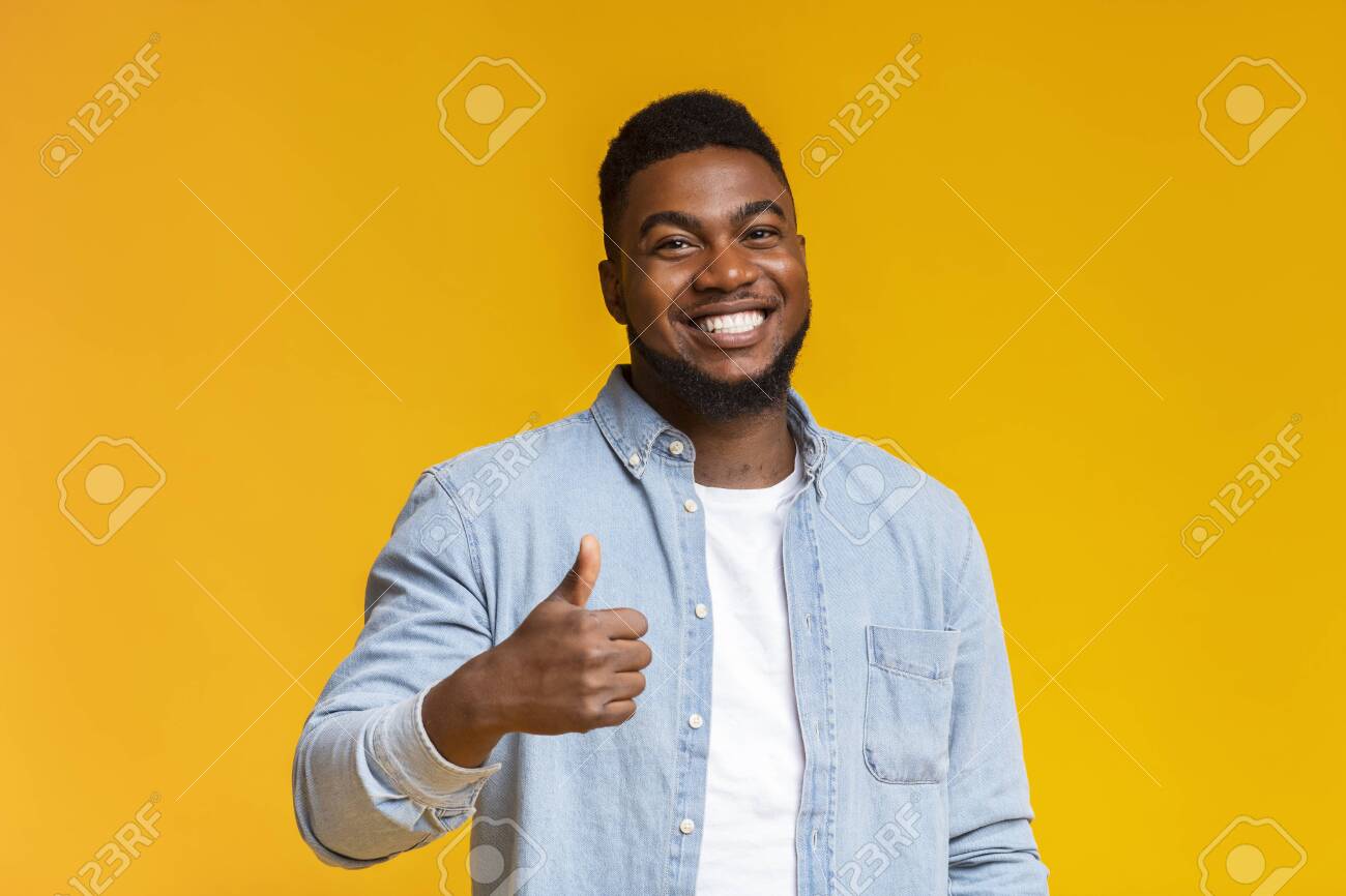 Right choice. Portrait of smiling blach guy showing thumb up at camera over yellow background with free space - 132853509 Right choice. Portrait of smiling blach guy showing thumb up at camera over yellow background with free space - 132853509