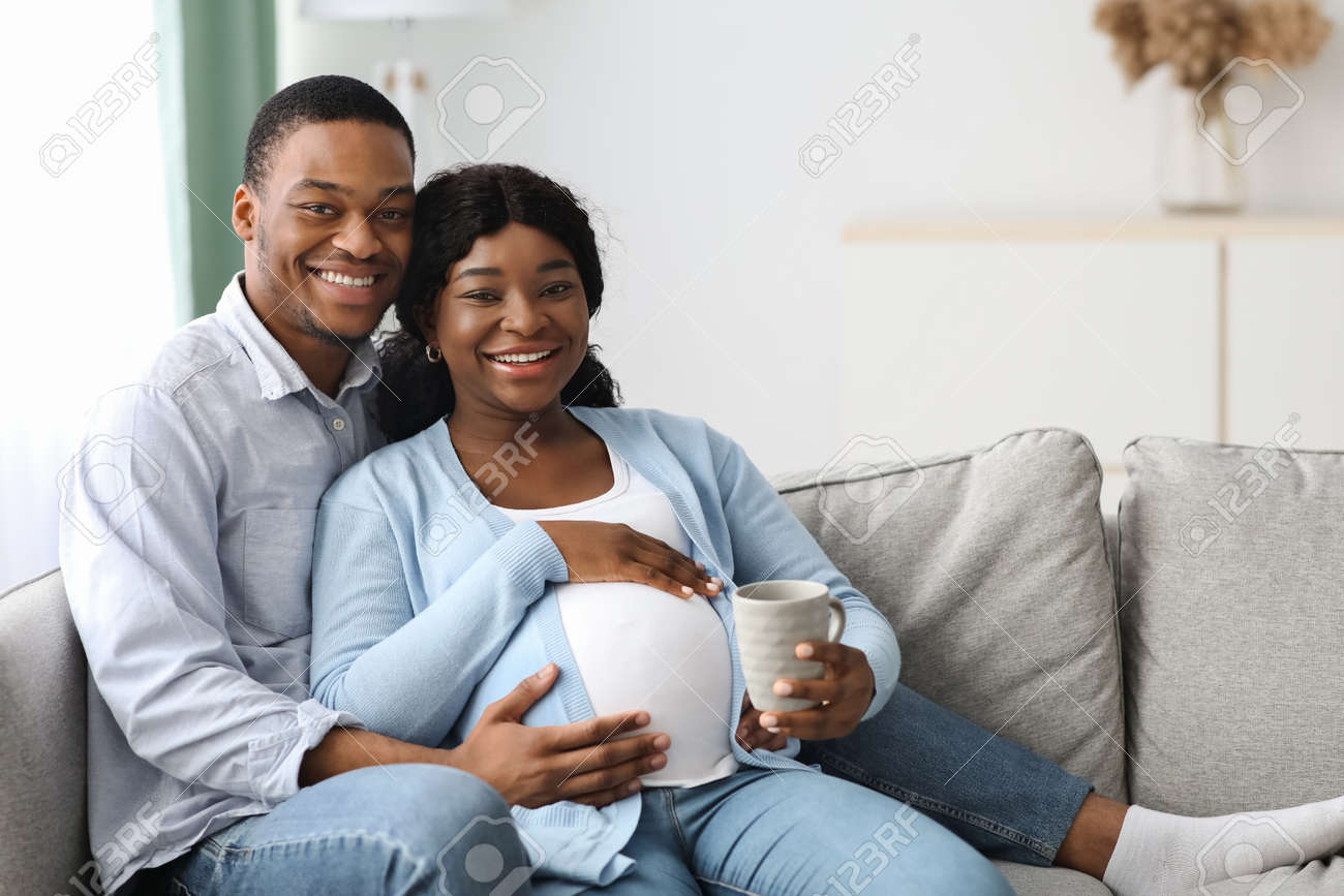 Happy Pregnant Black Couple Cuddling On Sofa At Home Stock Photo Picture And Royalty Free Image Image 166150063