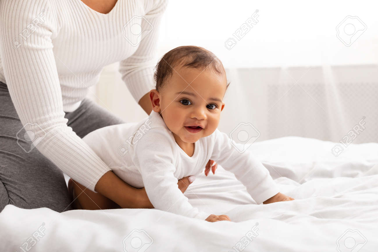 Unrecognizable Black Mom Helping Baby Son Crawl In Bedroom, Cropped - 167837931 Unrecognizable Black Mom Helping Baby Son Crawl In Bedroom, Cropped - 167837931