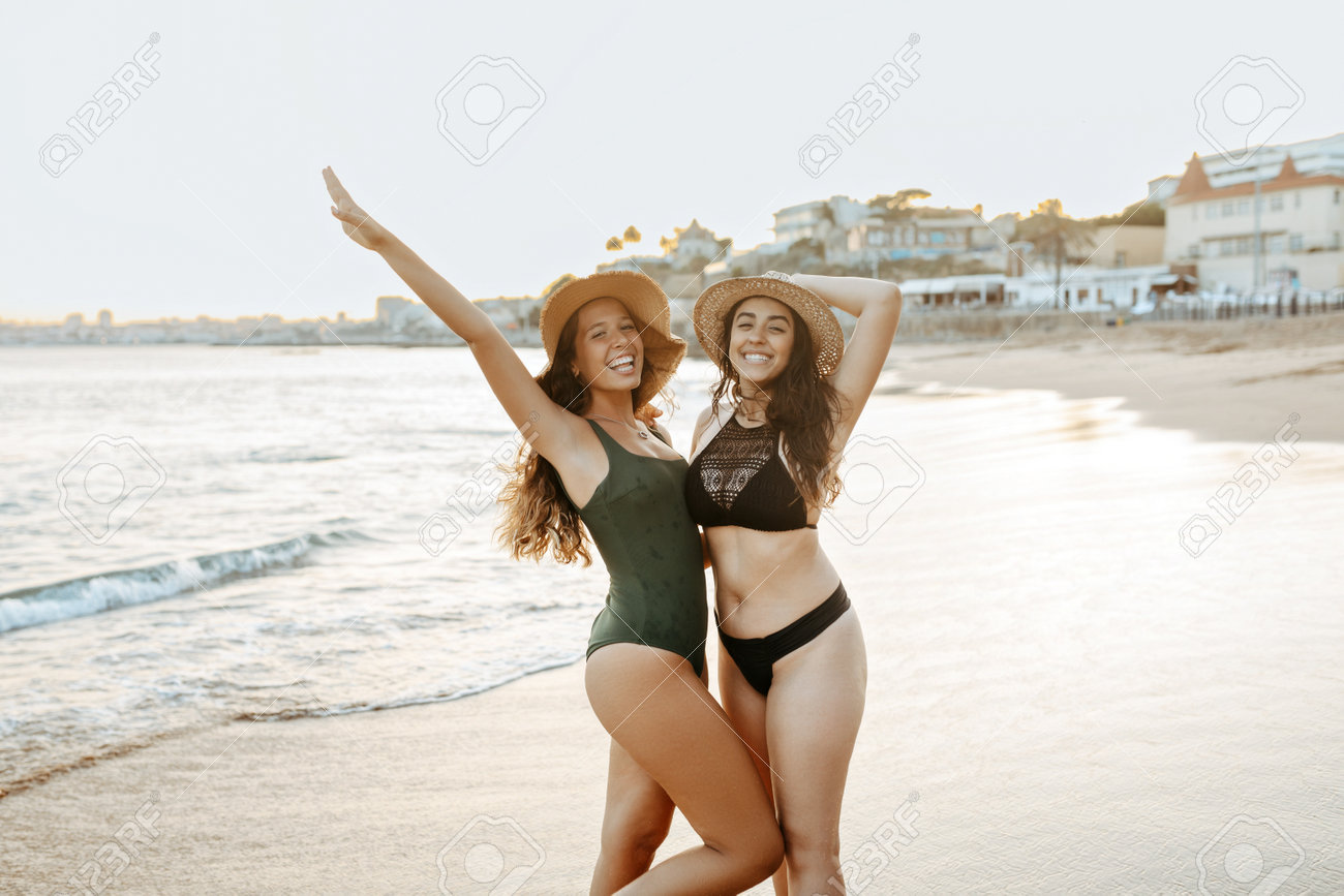 水着　ポートレート 夕方に海岸を歩く、水着と麦わら帽子を着た幸せな2人の女性の友人のポートレートの写真素材・画像素材 Image 208677531