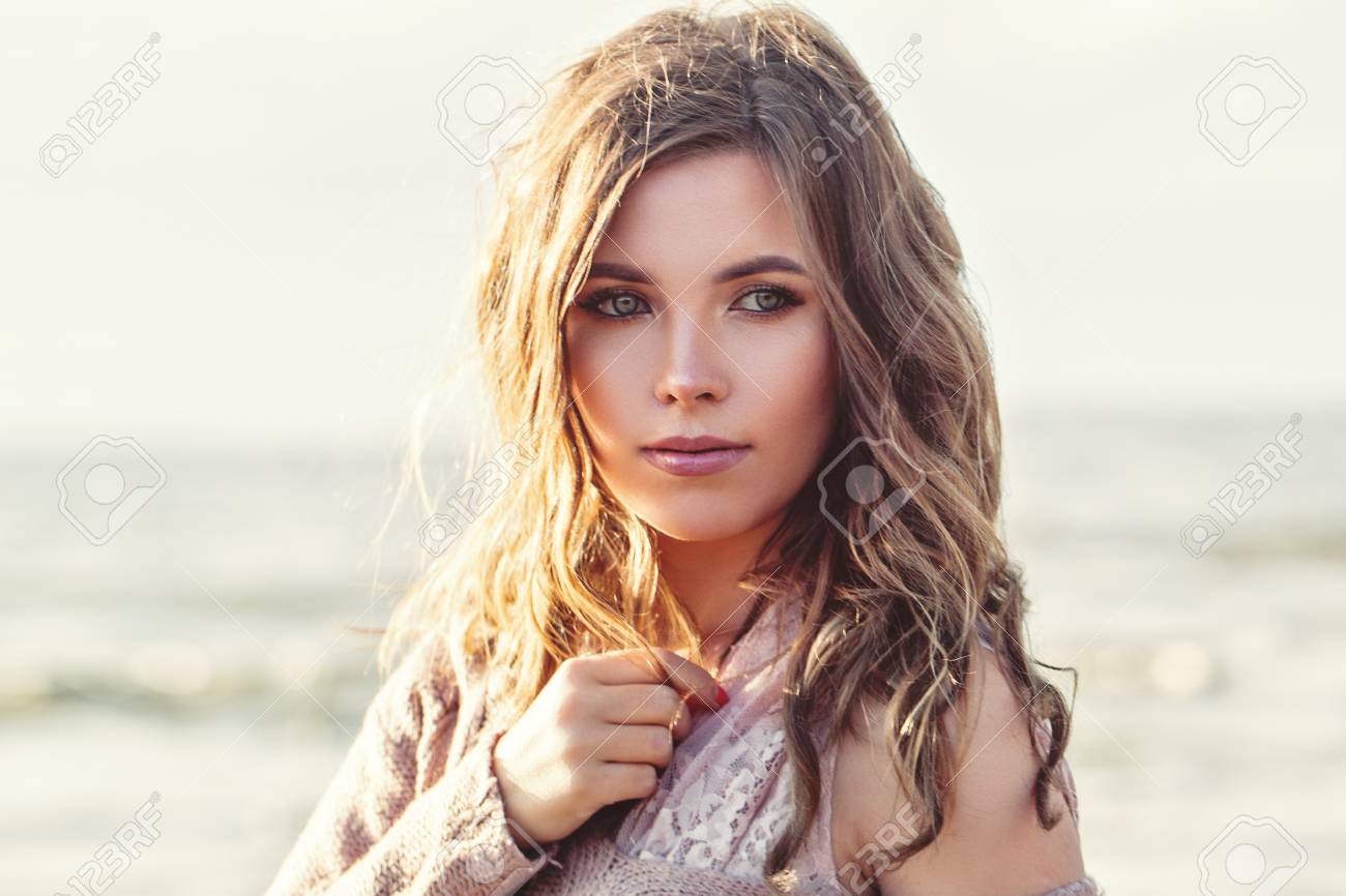 Beautiful woman face closeup portrait. Pretty girl with long curly brown hair on ocean background. Perfect natural beauty - 122127277 Beautiful woman face closeup portrait. Pretty girl with long curly brown hair on ocean background. Perfect natural beauty - 122127277