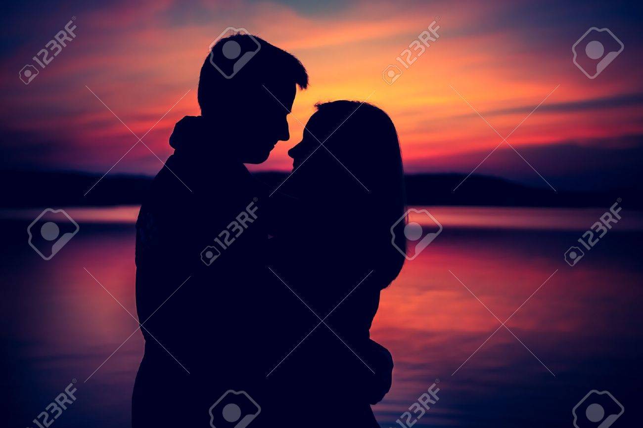 Silhouettes of hugging couple against the sunset sky. Photo with vintage mood. - 38511789 Silhouettes of hugging couple against the sunset sky. Photo with vintage mood. - 38511789