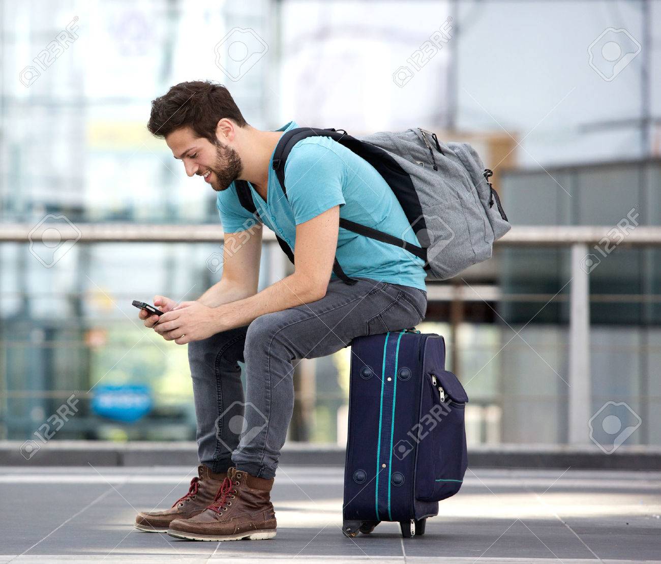 スーツケースの上に座ってとテキスト メッセージを送信する若い男性旅行者の肖像画 の写真素材 画像素材 Image スーツケースの上に座ってとテキスト メッセージを送信する若い男性旅行者の肖像画 の写真素材 画像素材 Image