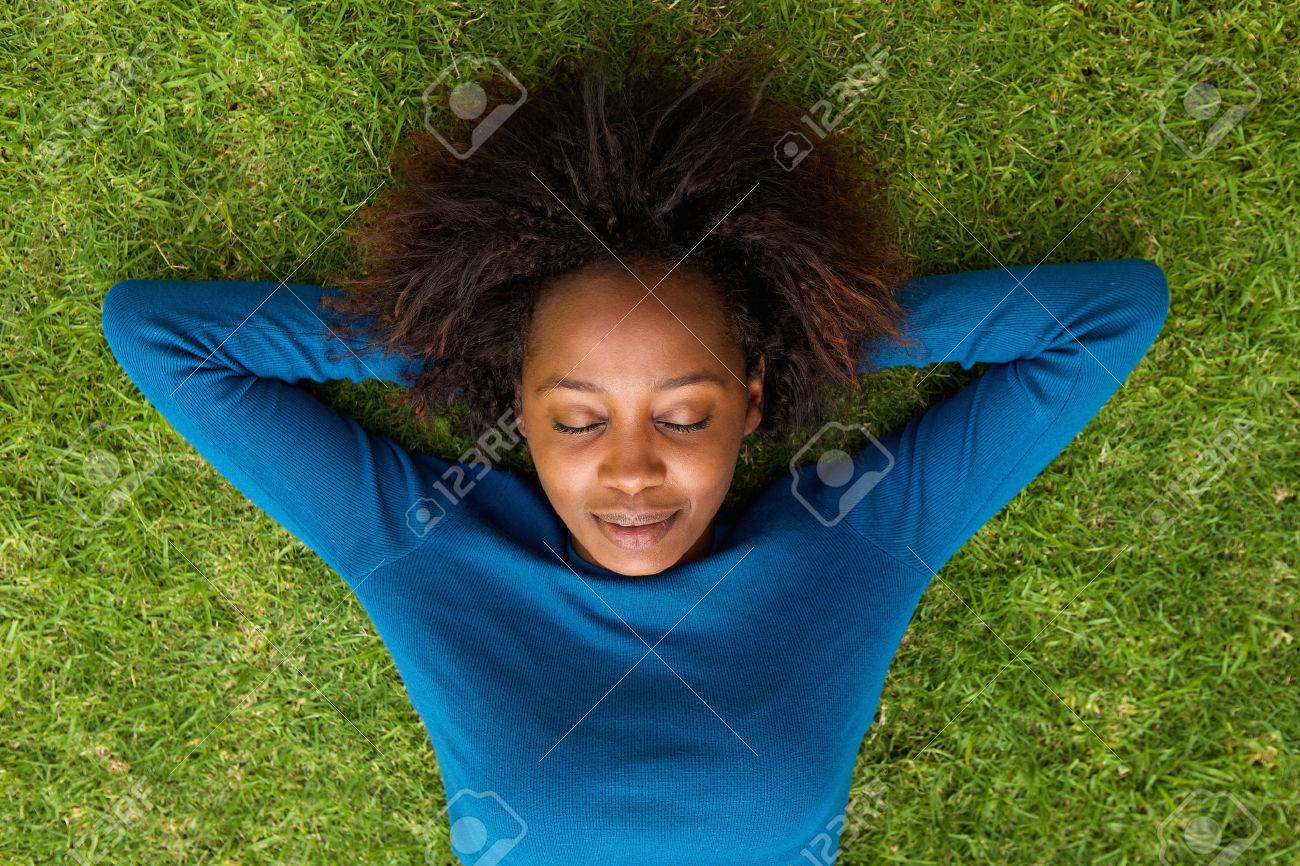 Portrait from above of a young african woman lying on grass sleeping - 53360178 Portrait from above of a young african woman lying on grass sleeping - 53360178