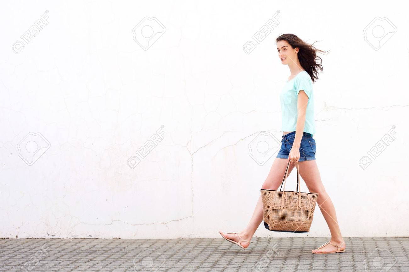 Full Length Side Portrait Of A Smiling Young Woman Walking With Handbag  Stock Photo, Picture and Royalty Free Image. Image 57421927., image size:1300x866