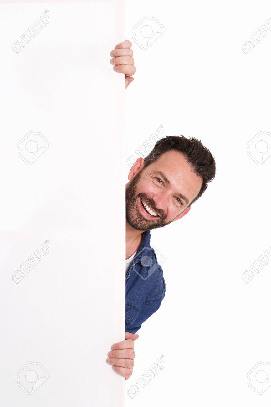 Portrait of smiling mature man peeking over blank poster sign against white background - 63536505 Portrait of smiling mature man peeking over blank poster sign against white background - 63536505