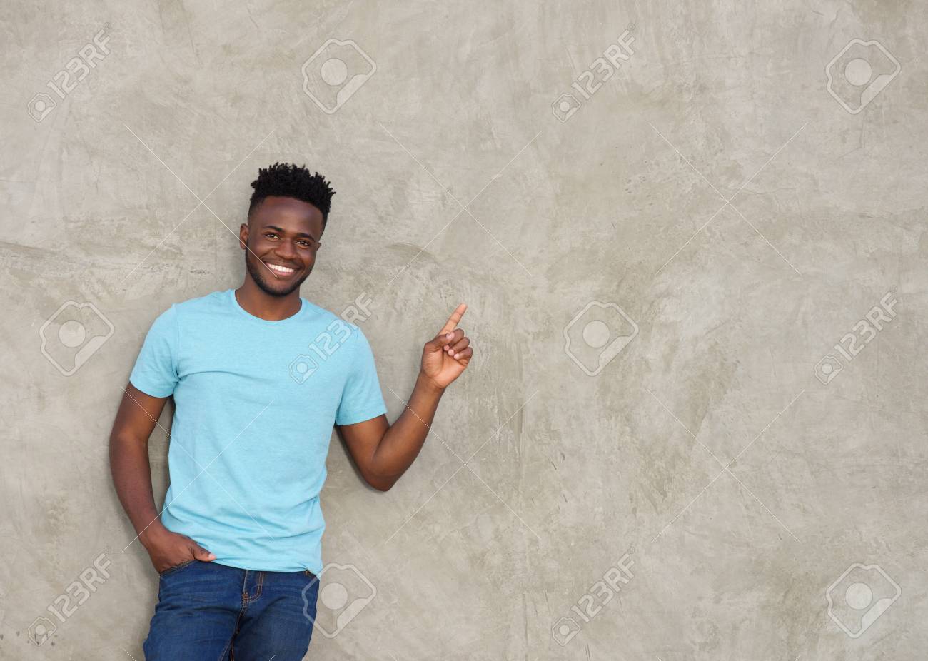 Portrait of confident young man pointing and smiling - 70484578 Portrait of confident young man pointing and smiling - 70484578