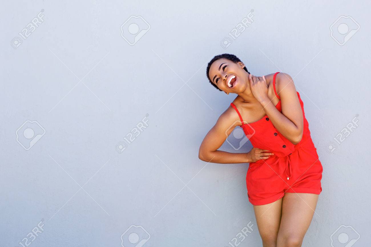 Portrait of cheerful young black woman laughing against gray wall - 71517557 Portrait of cheerful young black woman laughing against gray wall - 71517557
