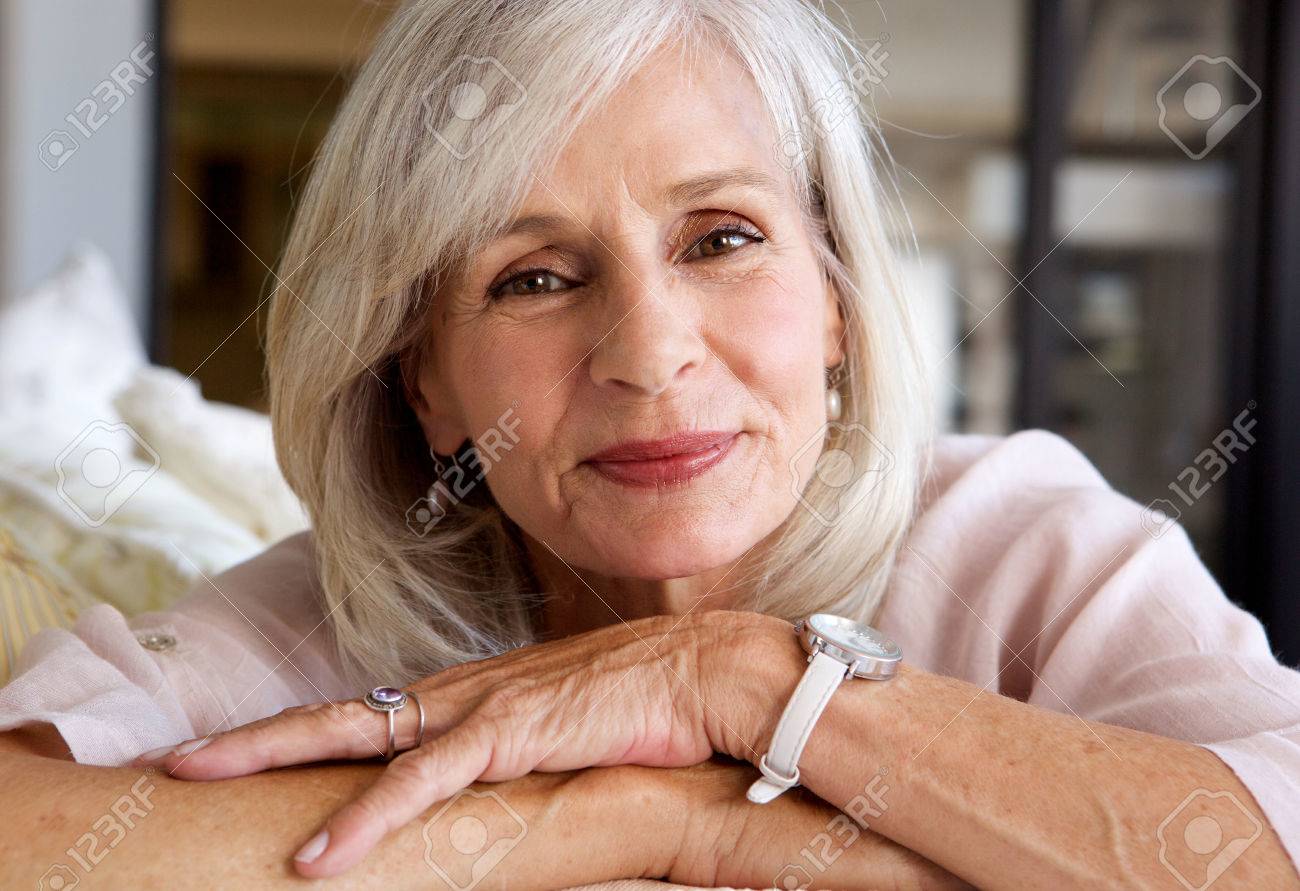 Close up portrait of relaxed older woman smiling and sitting on sofa - 74022186 Close up portrait of relaxed older woman smiling and sitting on sofa - 74022186