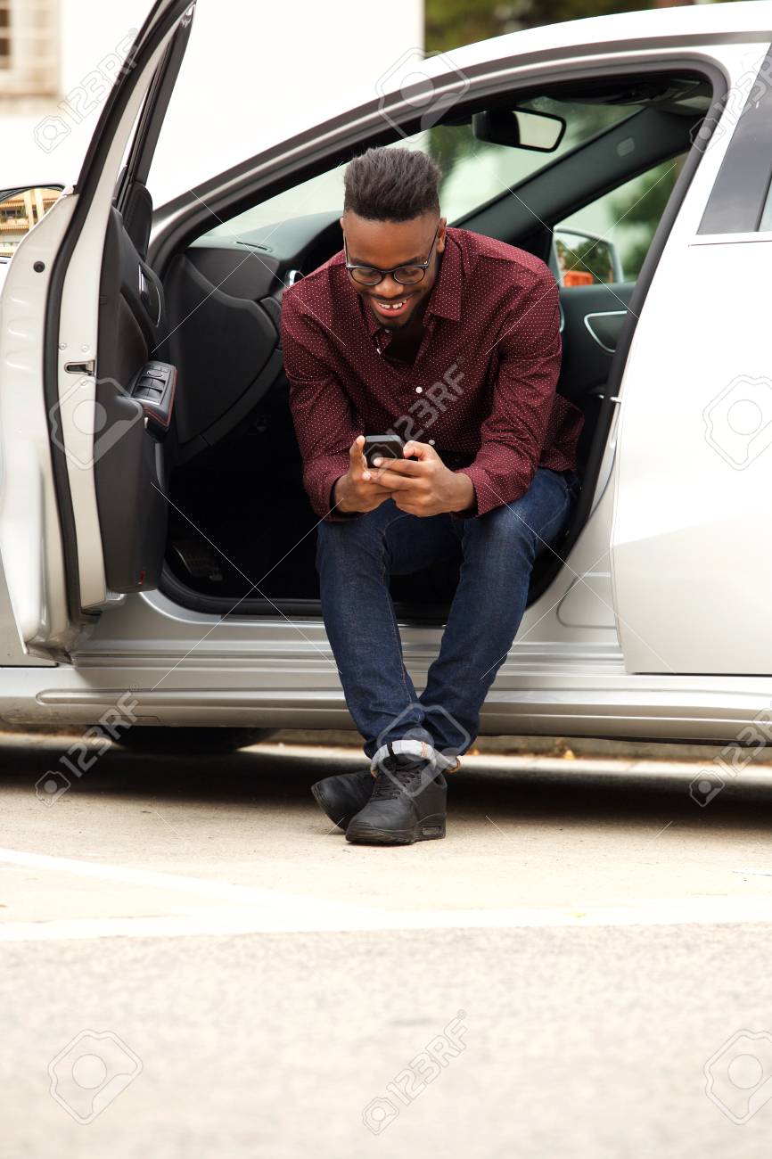 Portrait of african american man sitting in car sending text message - 93987257 Portrait of african american man sitting in car sending text message - 93987257