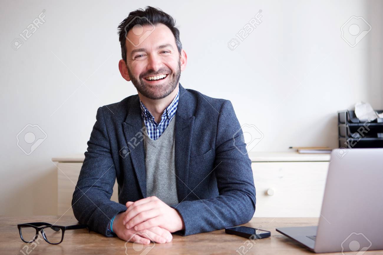 Portrait of smiling businessman sitting in office - 102938638 Portrait of smiling businessman sitting in office - 102938638