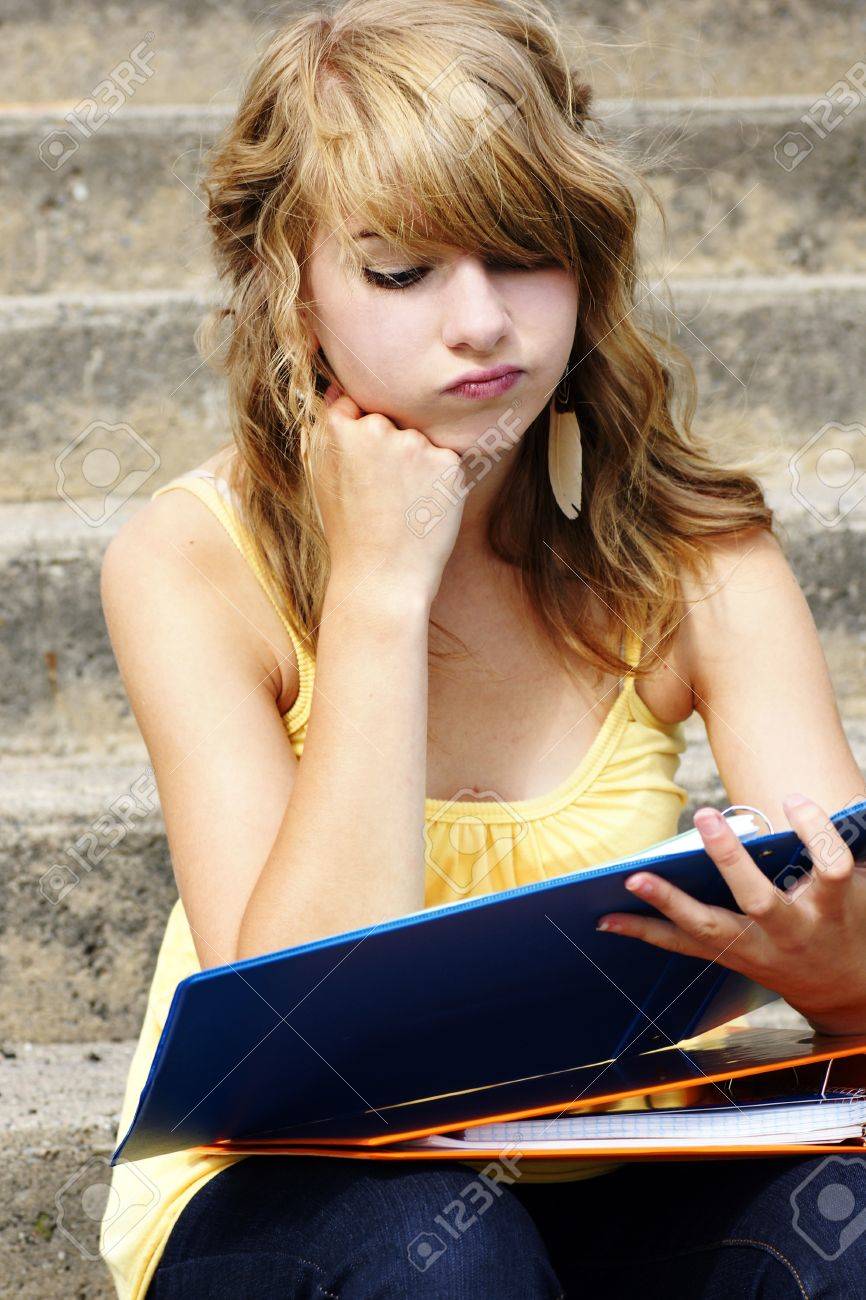 Stock Photo Unhappy Or Frustrated Young Blond Teenager Girl Going Back To School Or Looking At Her Homework In A Binder Stock Photo Unhappy Or Frustrated Young Blond Teenager Girl Going Back To School Or Looking At Her Homework In A Binder