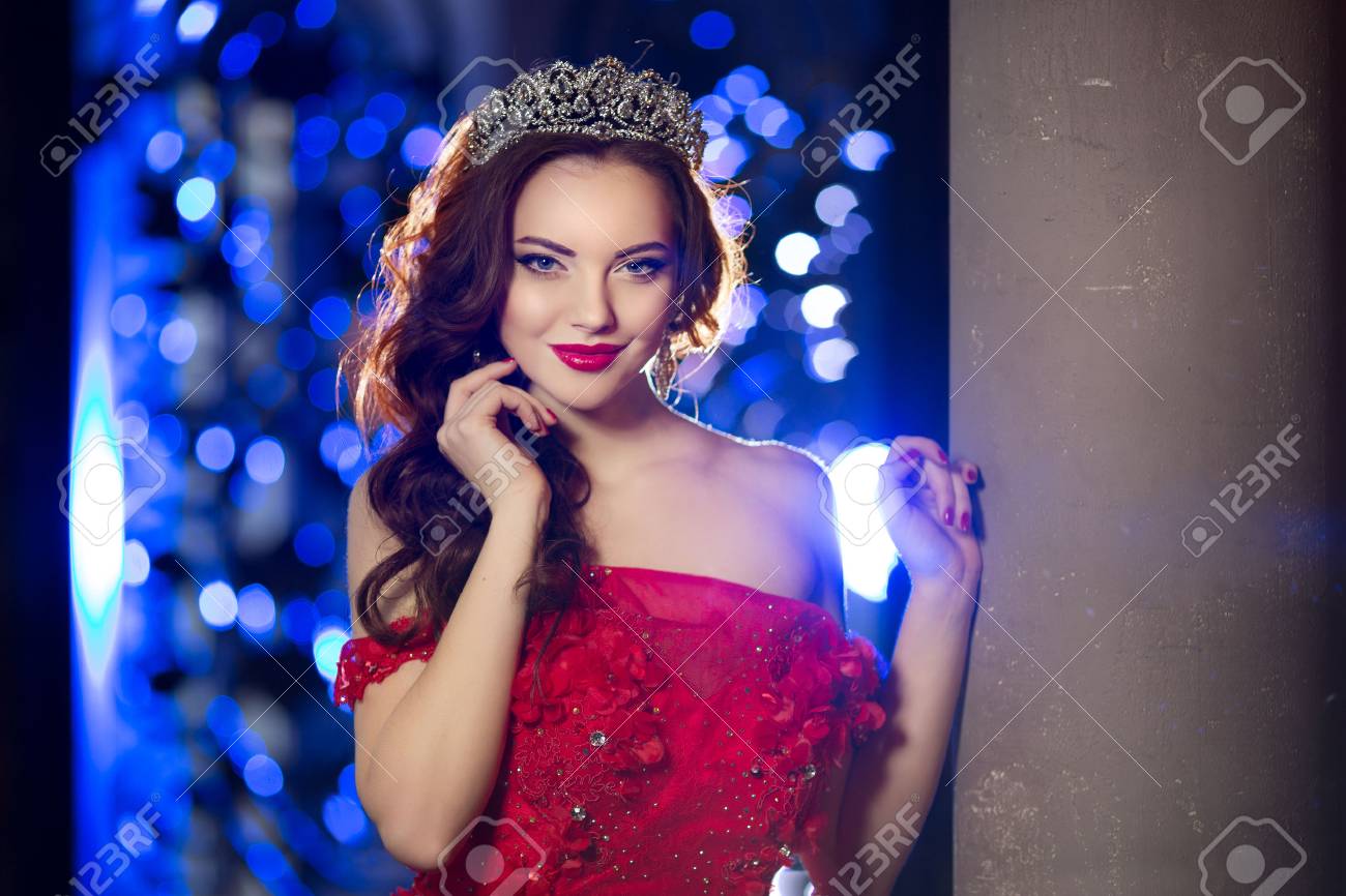 Frau In Lux Kleid Mit Krone Wie Konigin Prinzessin Leuchtet Partei Hintergrund Luxuxmadchen Lange Glanzend Gesundes Volumen Haar Waves Curls Updo Frisur Salon Mode Modell Luxuriose Haarschnitt Jahrgang Innenraum Schmuck Ohrringe Lizenzfreie Fotos