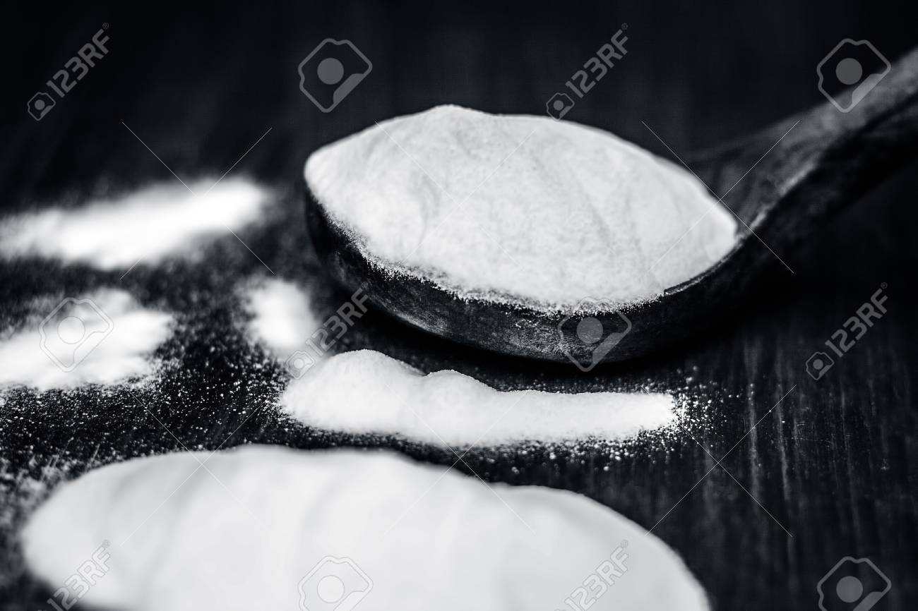 baking soda or sodium hydrogen carbonate in a wooden scoop on hydrogen carbonate
