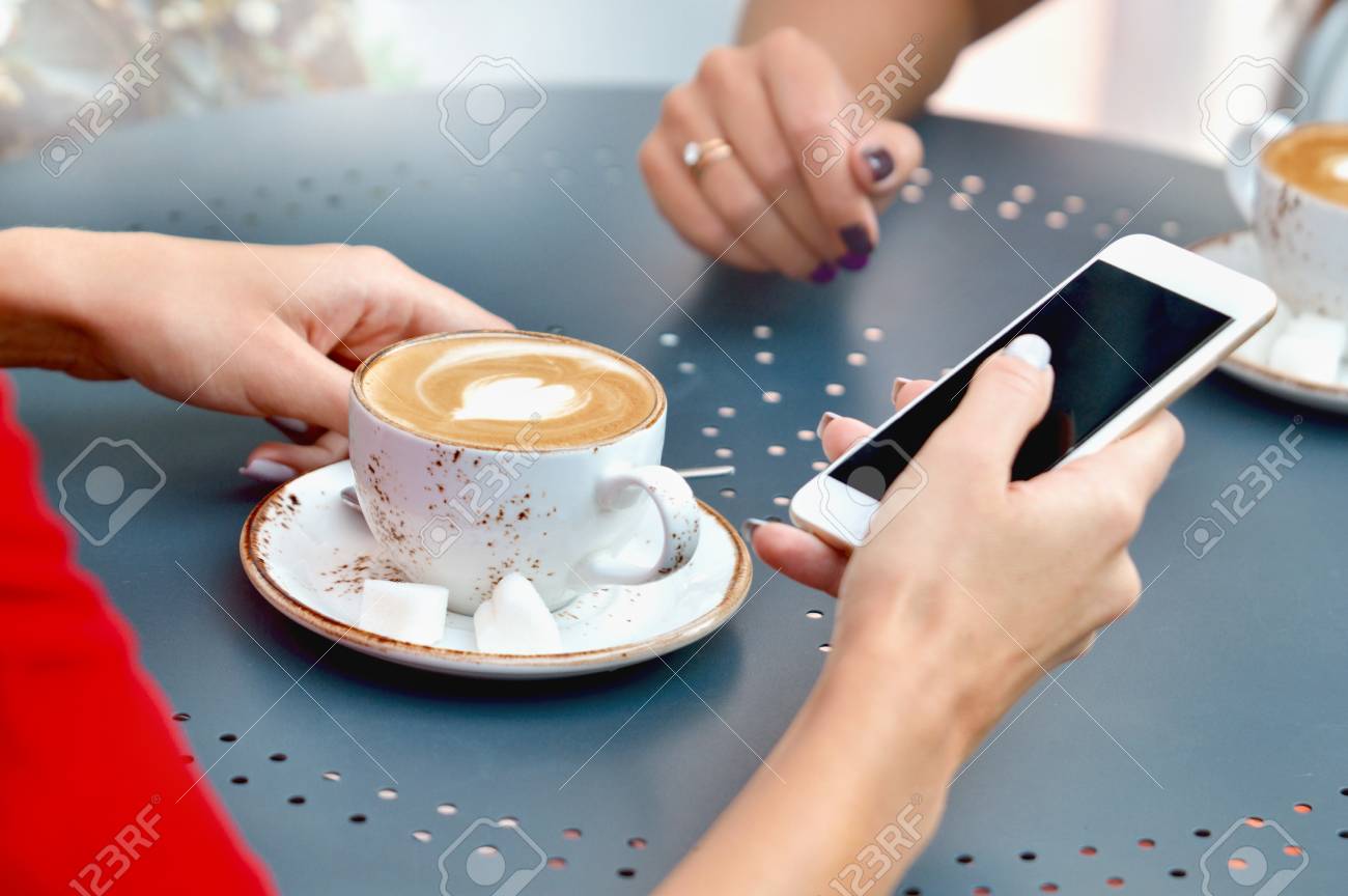 Close Up Blick Auf Zwei Kaffeetassen Und Hande Von Jungen Frauen Mit Smartphone Im Outdoor Cafe Lifestyle Freundschaft Und Technologie Konzept Lizenzfreie Fotos Bilder Und Stock Fotografie Image