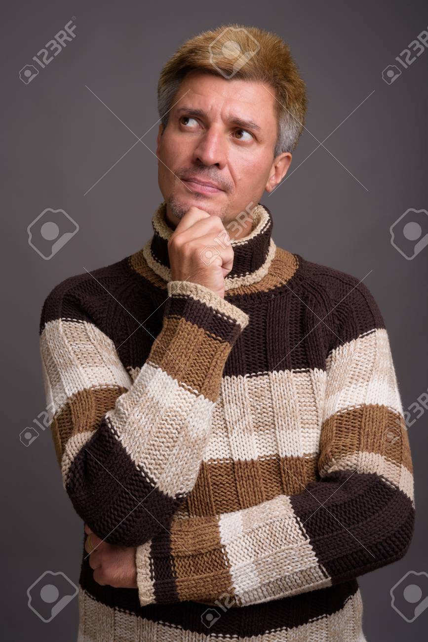 Man With Blond Hair Wearing Turtleneck Sweater Against Gray Back