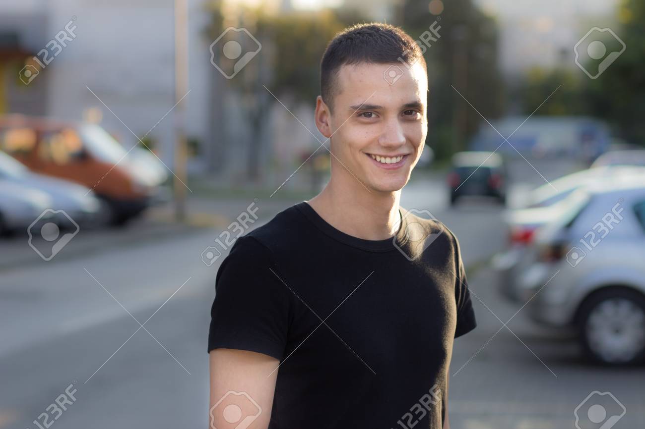 Junger Mann in den frühen 20er Jahren Portrait lächelnd im Freien Geringe Schärfentiefe Verwischen