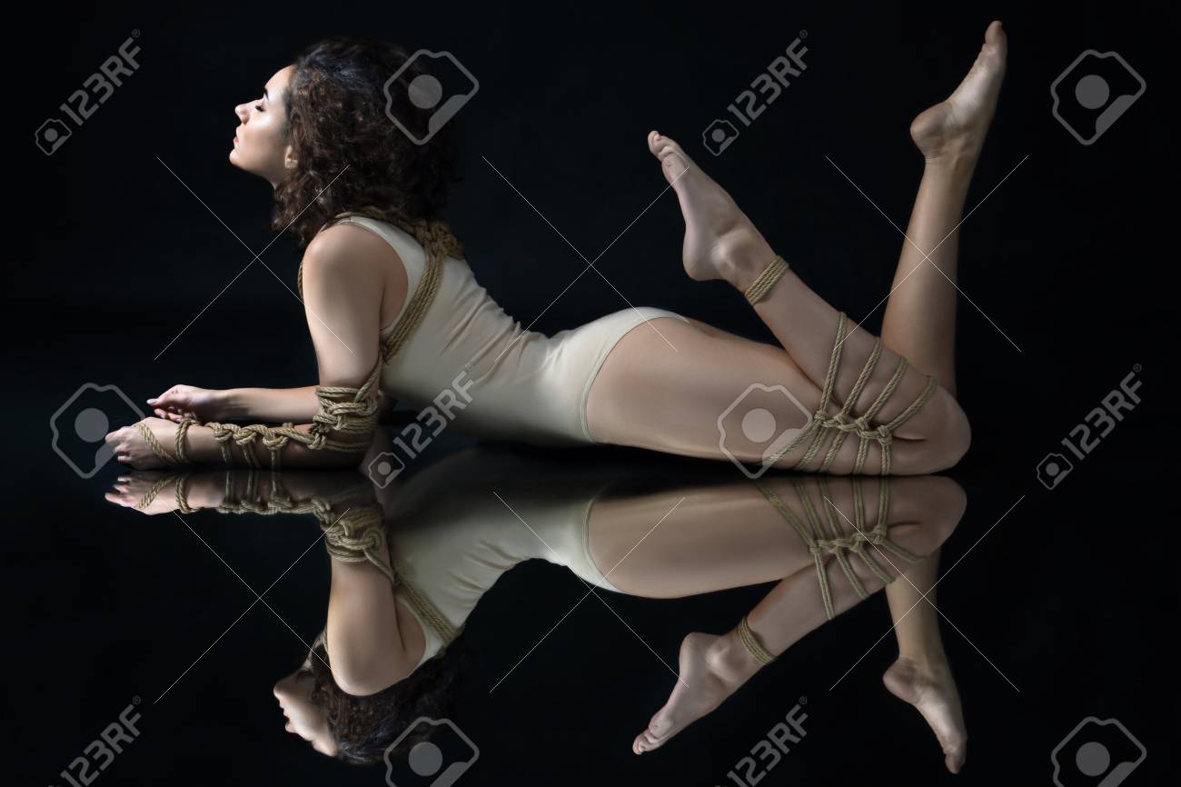 Andrii StarunskyiSubmission Slave Woman Bound In Erotic Fashion Style Rope Shibari Kinbaku Japanese Bondage Knot Lie On Floor With Symmetry Reflection Bdsm Mistress Dominant Fetish Punishment Sadism Masochism Concept image