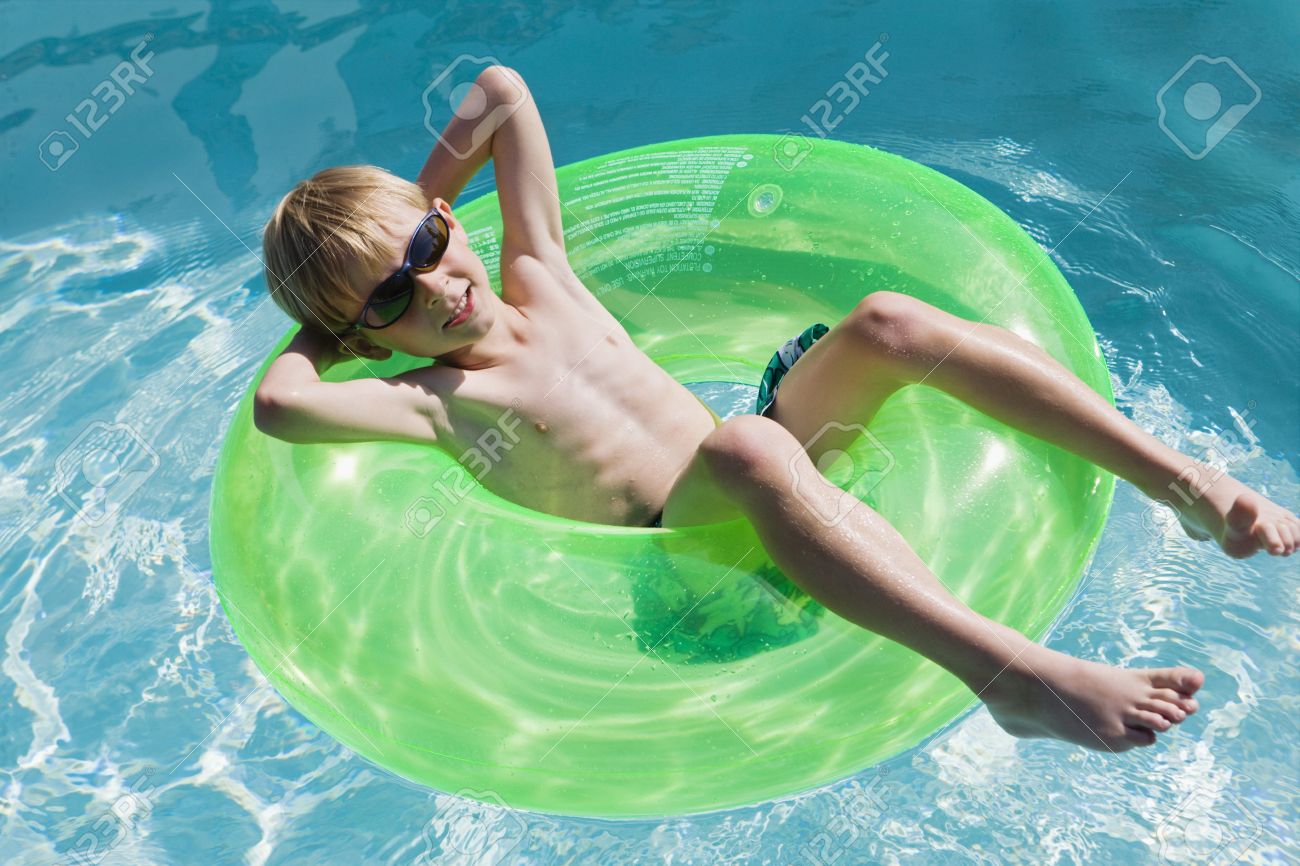 Boy on Float Tube in Swimming Pool - 12592904.