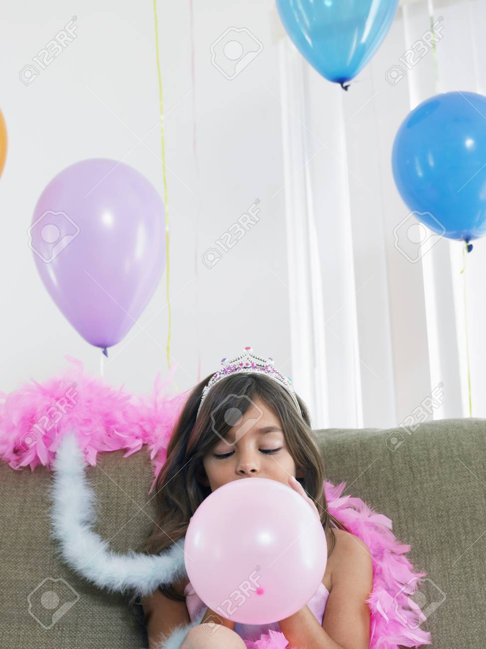 Young Girl 7 9 Sitting On Sofa Blowing Up Balloon Young Girl 7 9 Sitting On Sofa Blowing Up Balloon