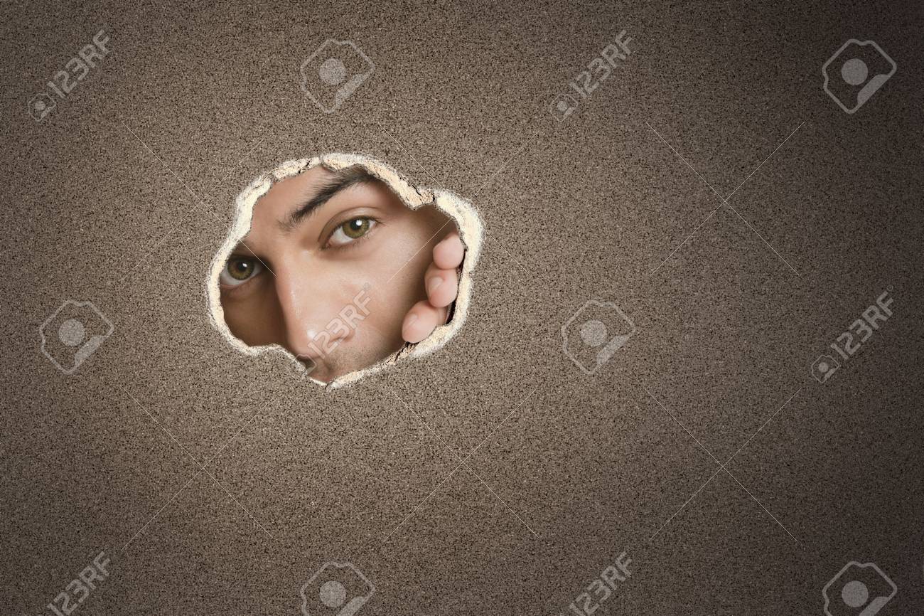 紙の穴から覗く若いアジア人の男性の肖像画 の写真素材 画像素材 Image