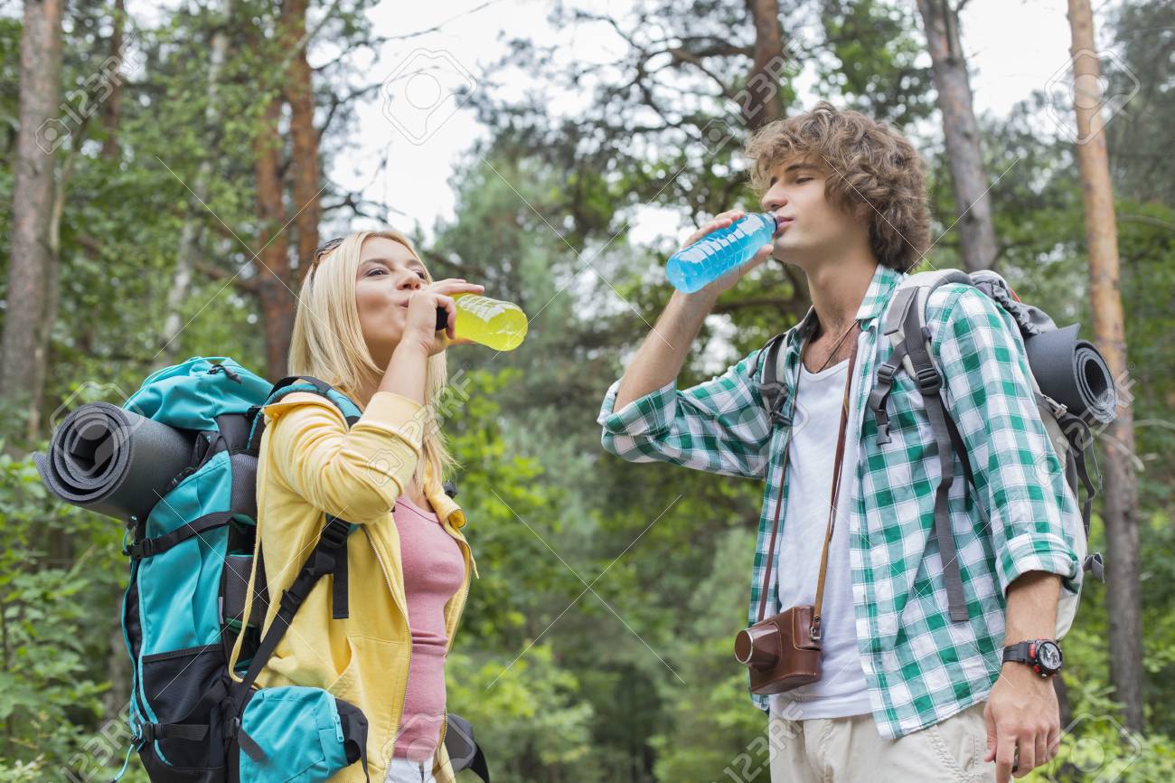 Young hiking couple drinking energy drinks in forest - 33862004 Young hiking couple drinking energy drinks in forest - 33862004