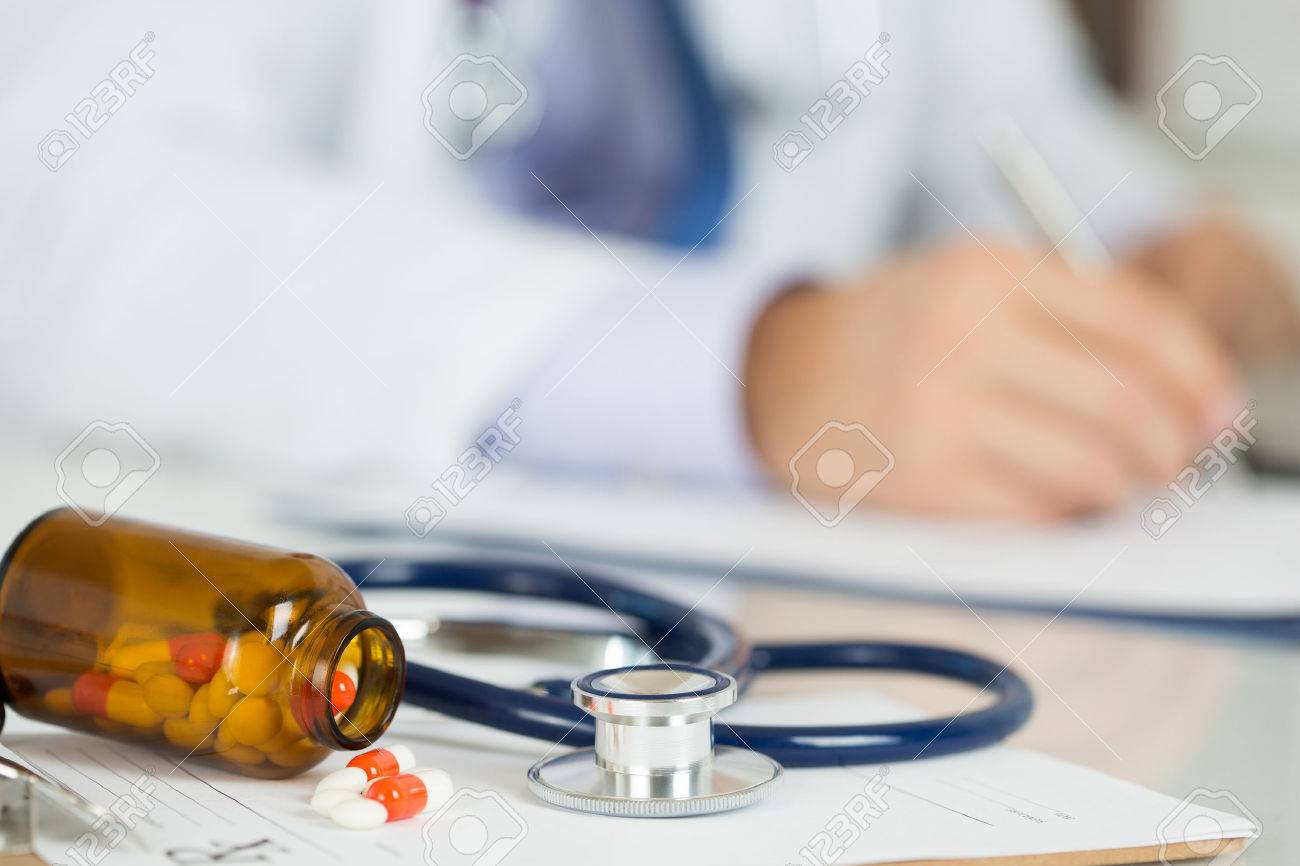 Pills and stethoscope laying on clipping board with prescription blank with male medicine doctor working on background. Medicine doctor's working table. Healthcare and medical concept. Copyspace - 46777406 Pills and stethoscope laying on clipping board with prescription blank with male medicine doctor working on background. Medicine doctor's working table. Healthcare and medical concept. Copyspace - 46777406
