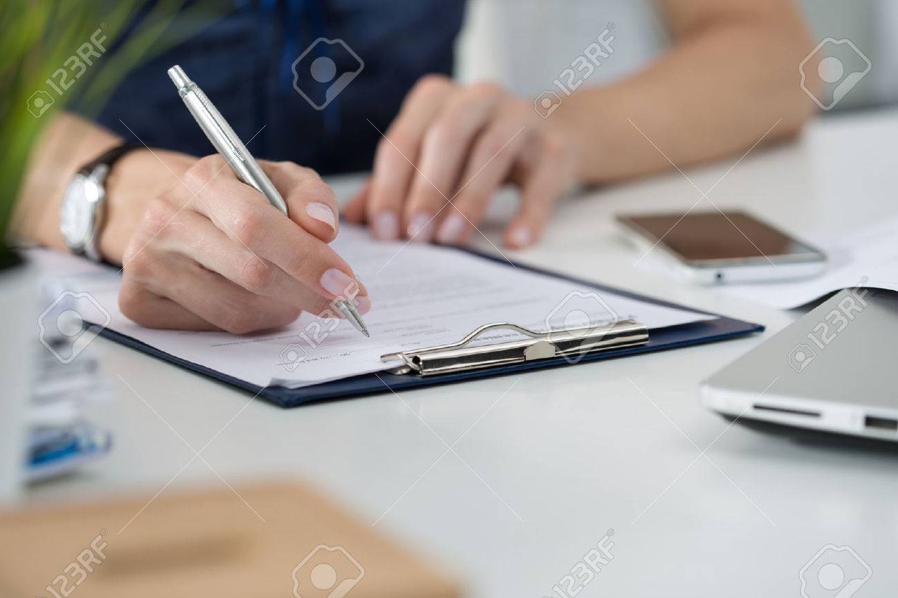 Close-up of female hands. Woman writing something sitting at her office. Signing documents - 46777539 Close-up of female hands. Woman writing something sitting at her office. Signing documents - 46777539