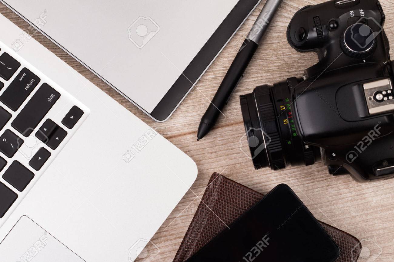 Close-up top view of photographer of graphic designer workplace. Laptop, graphic tablet, phone and photo camera on wooden table. - 54703811 Close-up top view of photographer of graphic designer workplace. Laptop, graphic tablet, phone and photo camera on wooden table. - 54703811