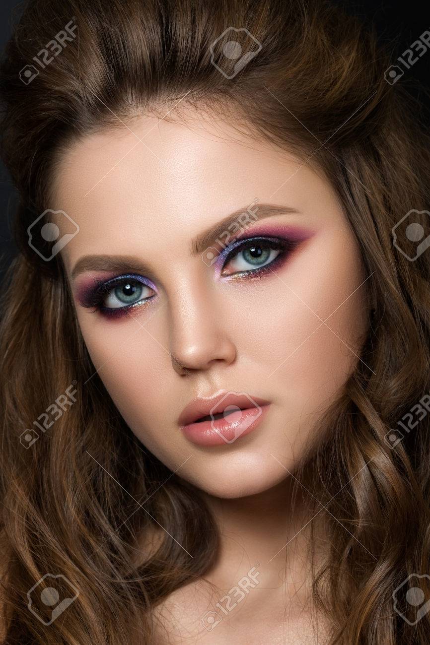 Close up portrait of young beautiful woman with purple evening make up over black background. Modern fashion smokey eyes makeup. Studio shot. - 56057666 Close up portrait of young beautiful woman with purple evening make up over black background. Modern fashion smokey eyes makeup. Studio shot. - 56057666