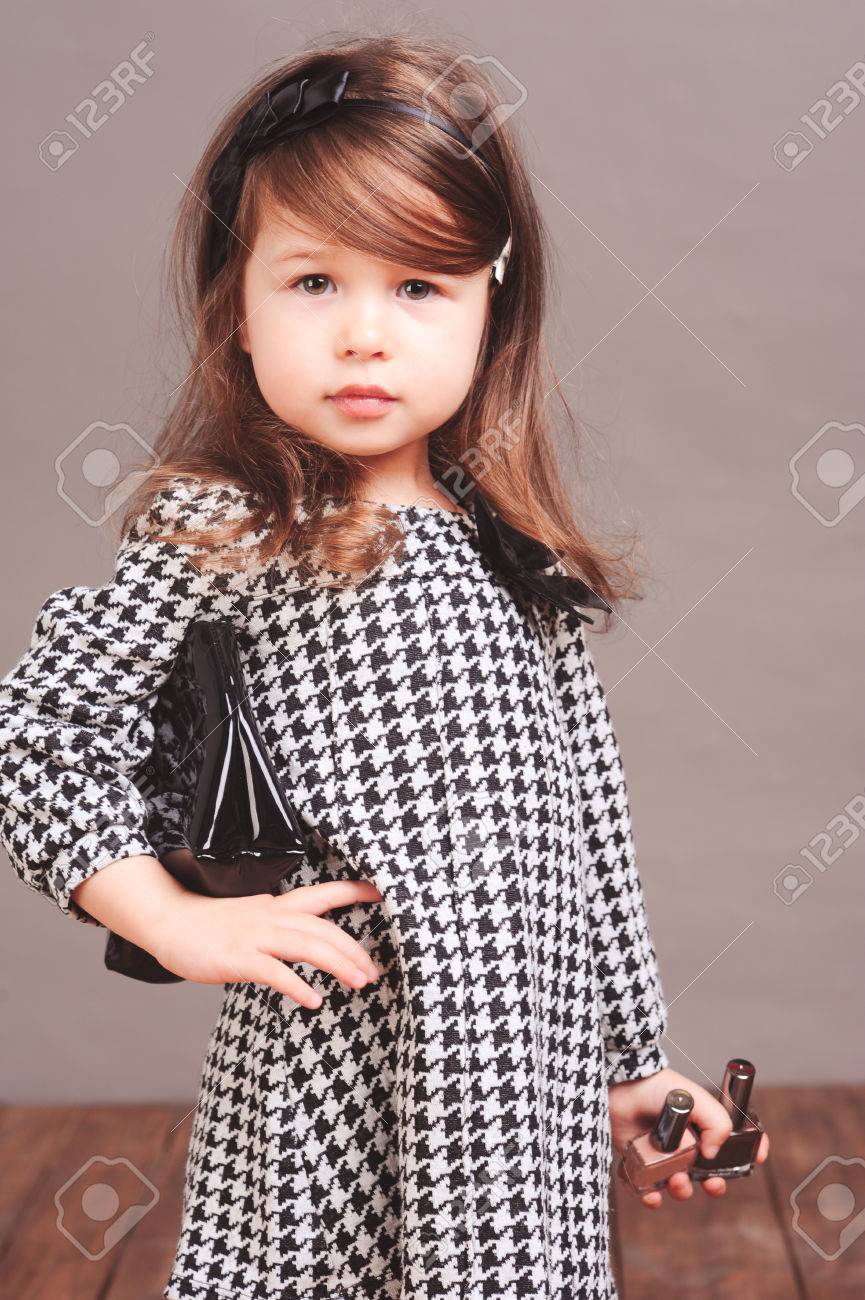 スタイリッシュな子供女の子 4 5 歳身に着けているトレンディなドレス 黒い革のバッグとヘアバンドを保持しています カメラを見ています 若いモデル の写真素材 画像素材 Image