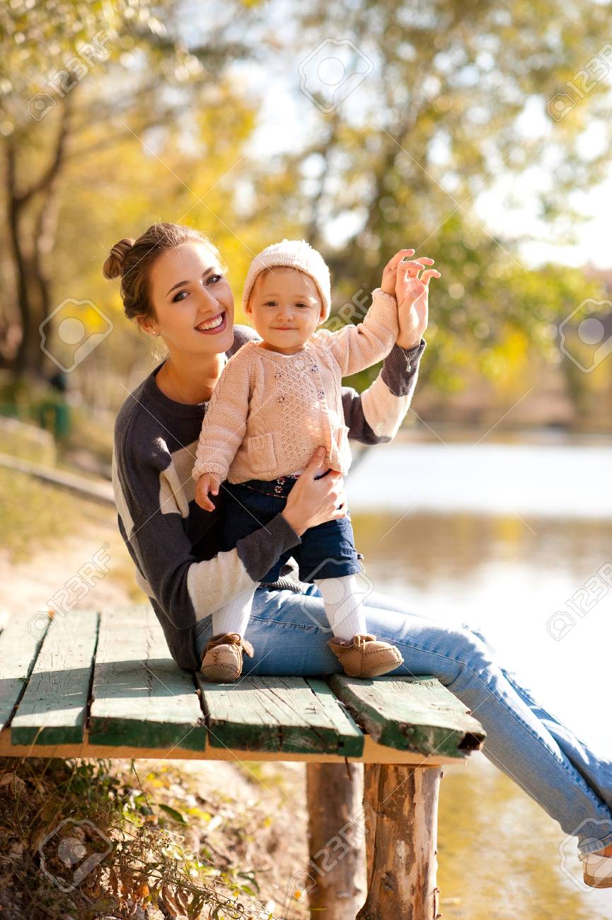 Souriant Mere Tenant Bebe Fille 1 An Portant Des Vetements Decontractes Tricotes Assis Dans Le Parc Automne Regardant La Camera Maternite Banque D Images Et Photos Libres De Droits Image