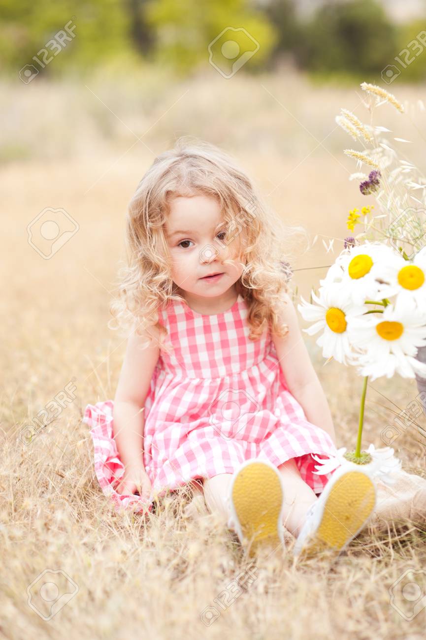 かわいい赤ちゃん女の子 2 3 歳座って屋外の花を持つ カメラを見ています 子供の頃 の写真素材 画像素材 Image