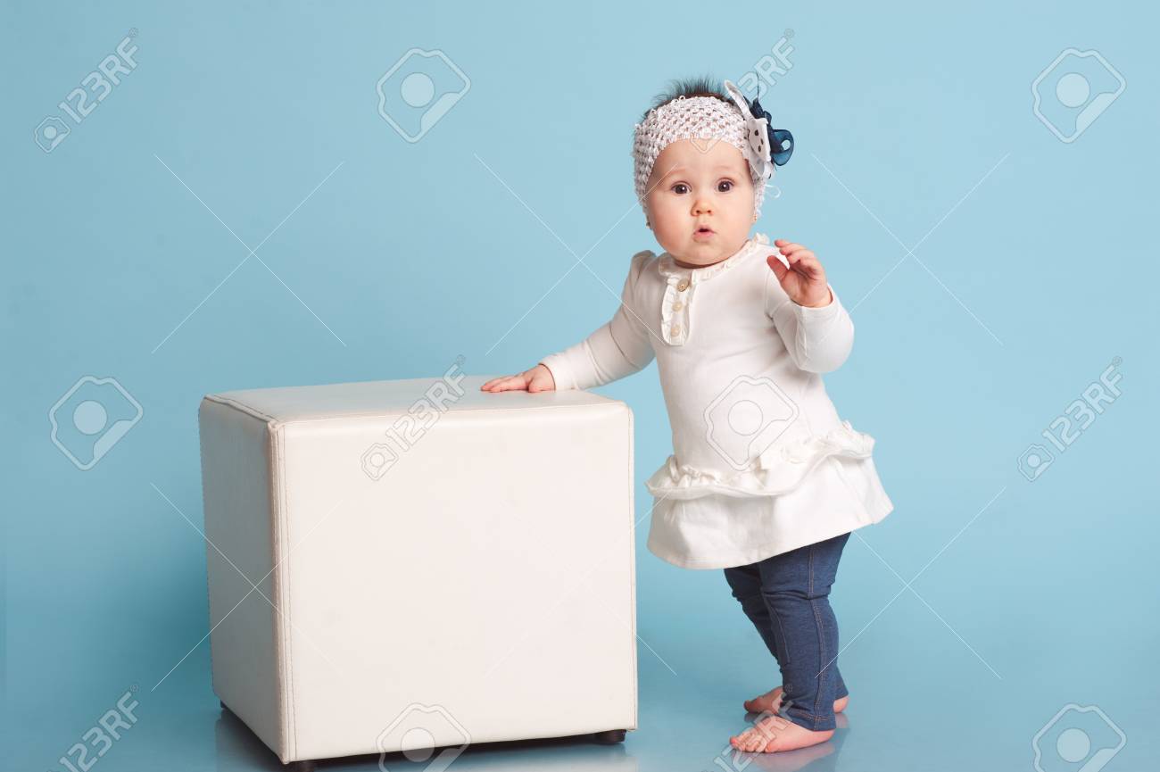 青の部屋で立って面白い子女の子 最初の手順を実行します 流行の服を着ています カメラを見ています 子供の頃 の写真素材 画像素材 Image