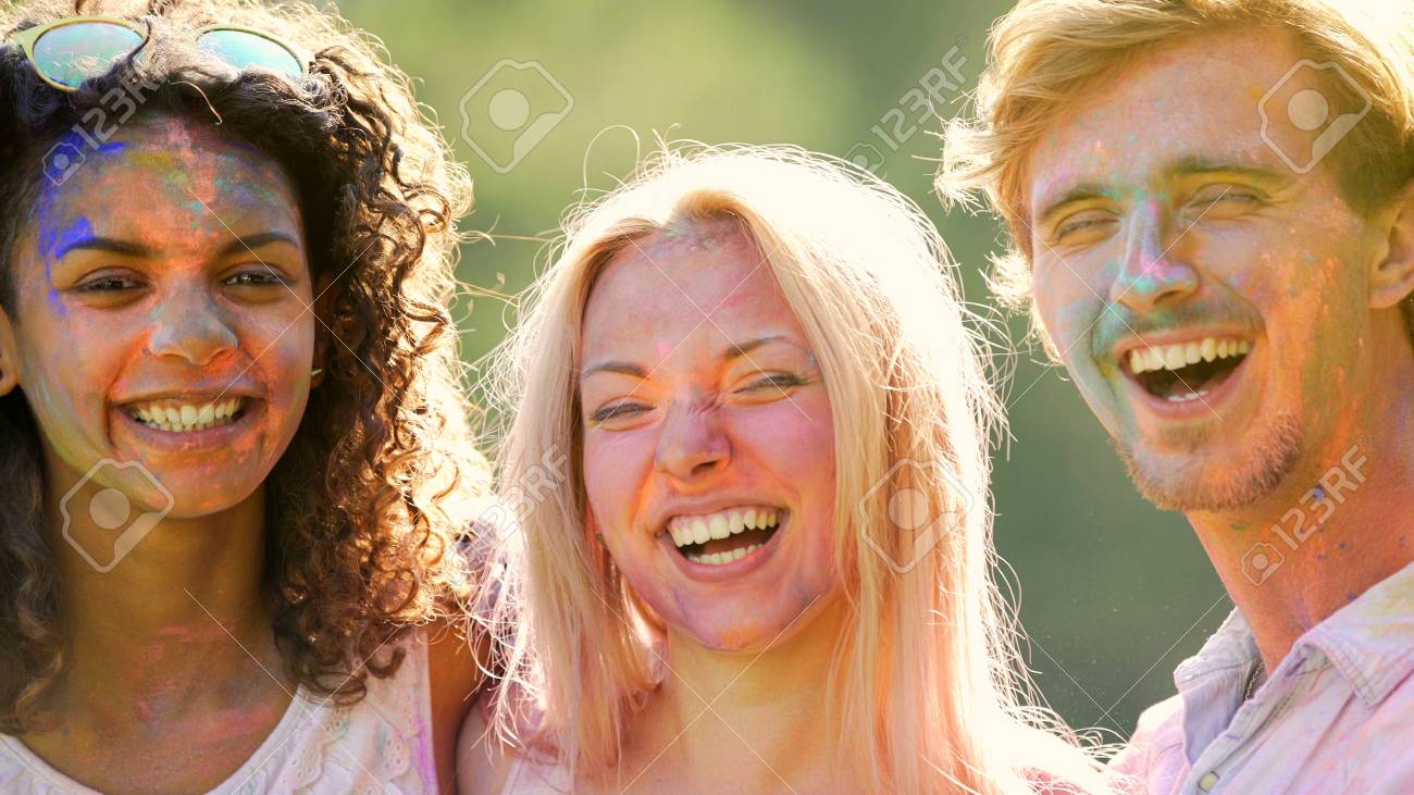 cheerful smiling faces of young people having fun at holi