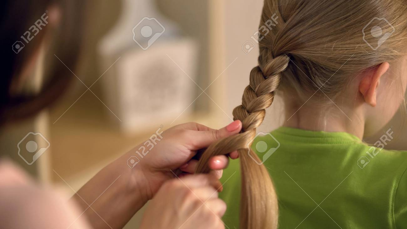 big sister or babysitter braiding little girls hair woman taking big babysitter
