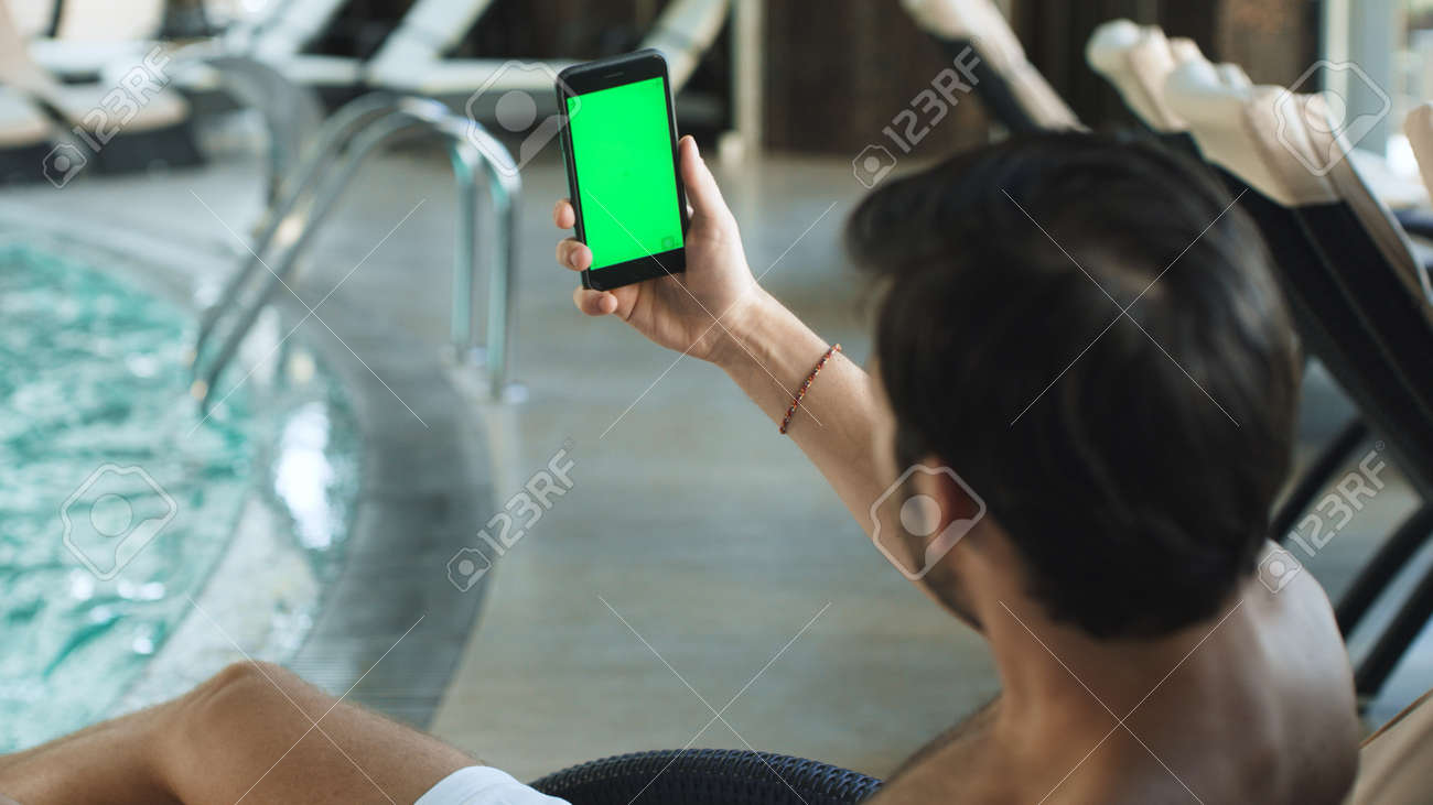 Closeup handsome man having video call with green screen phone. Sexy guy talking to green screen mobile poolside. Young man call video chat on phone near swimming pool. - 159370355 Closeup handsome man having video call with green screen phone. Sexy guy talking to green screen mobile poolside. Young man call video chat on phone near swimming pool. - 159370355