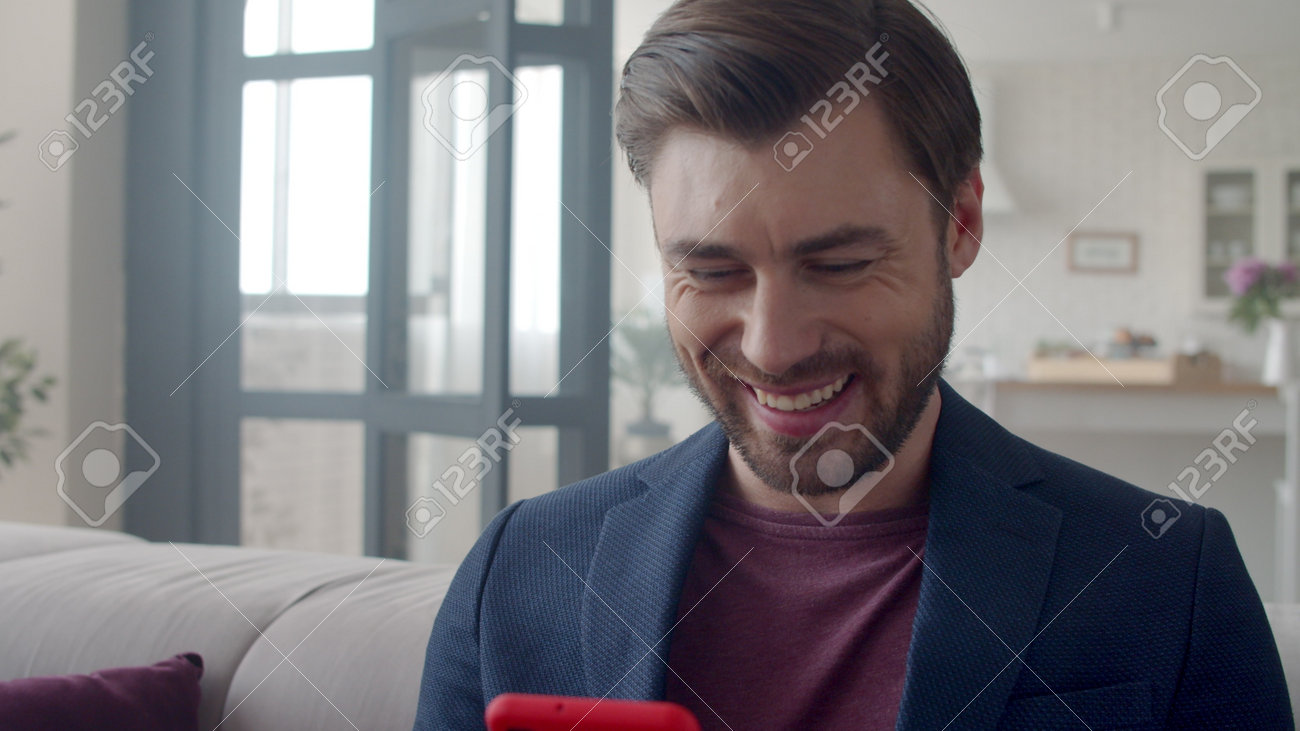 Closeup handsome business man laughing with phone at home. Portrait of smiling guy reading funny text on phone in flat. Joyful man surfing internet on smartphone on sofa. Guy reading funny email . - 162271088 Closeup handsome business man laughing with phone at home. Portrait of smiling guy reading funny text on phone in flat. Joyful man surfing internet on smartphone on sofa. Guy reading funny email . - 162271088